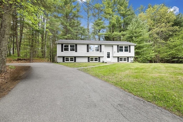 raised ranch with a front lawn, asphalt driveway, and entry steps