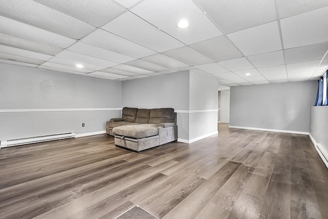 living area featuring a baseboard heating unit, wood finished floors, baseboards, a paneled ceiling, and recessed lighting