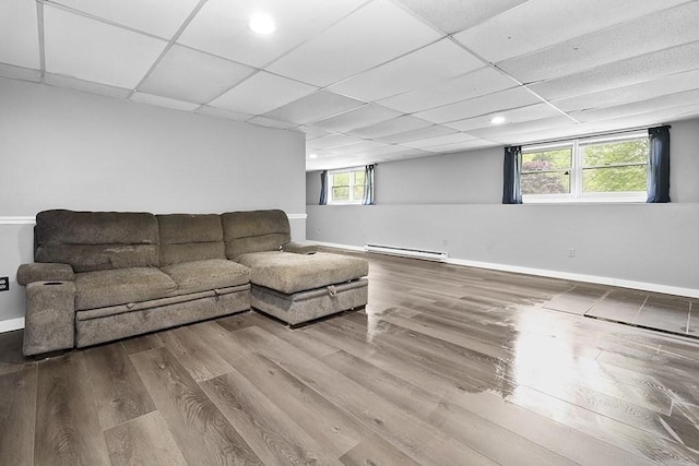living area featuring baseboard heating, wood finished floors, a paneled ceiling, baseboards, and recessed lighting
