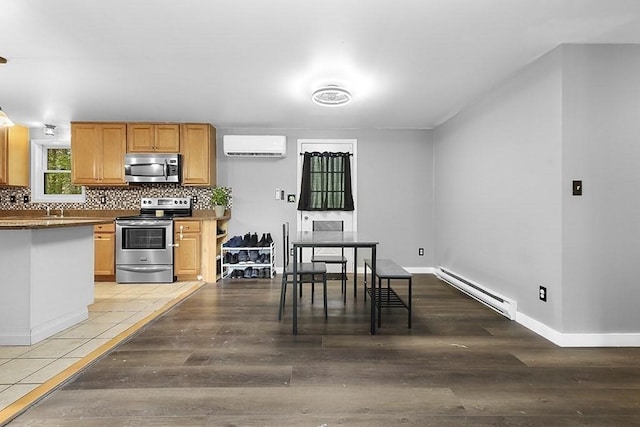 kitchen featuring appliances with stainless steel finishes, a baseboard radiator, light wood-style flooring, and decorative backsplash
