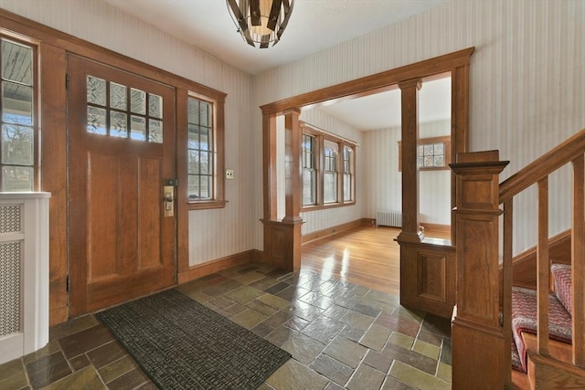 foyer featuring radiator, stone tile flooring, stairway, and baseboards