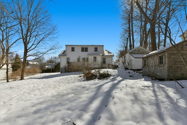 snow covered rear of property featuring a storage shed and an outdoor structure