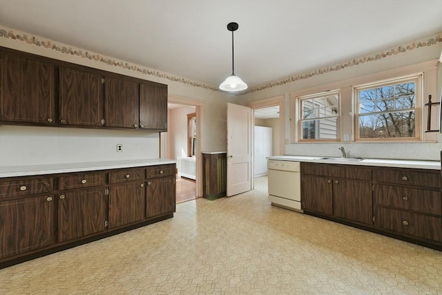 kitchen featuring dishwasher, light countertops, dark brown cabinets, and a sink