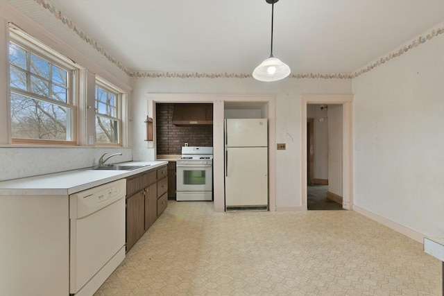 kitchen featuring white appliances, a sink, baseboards, light countertops, and decorative light fixtures