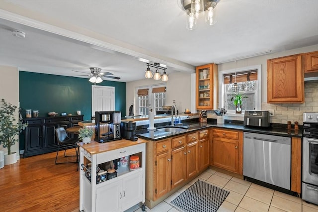 kitchen featuring a healthy amount of sunlight, brown cabinets, stainless steel appliances, and a sink