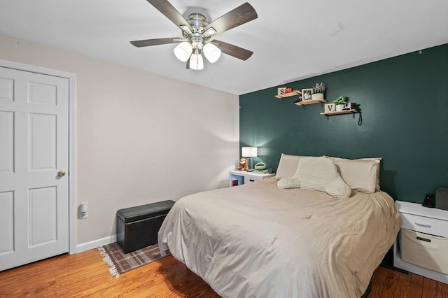 bedroom featuring a ceiling fan, baseboards, and wood finished floors