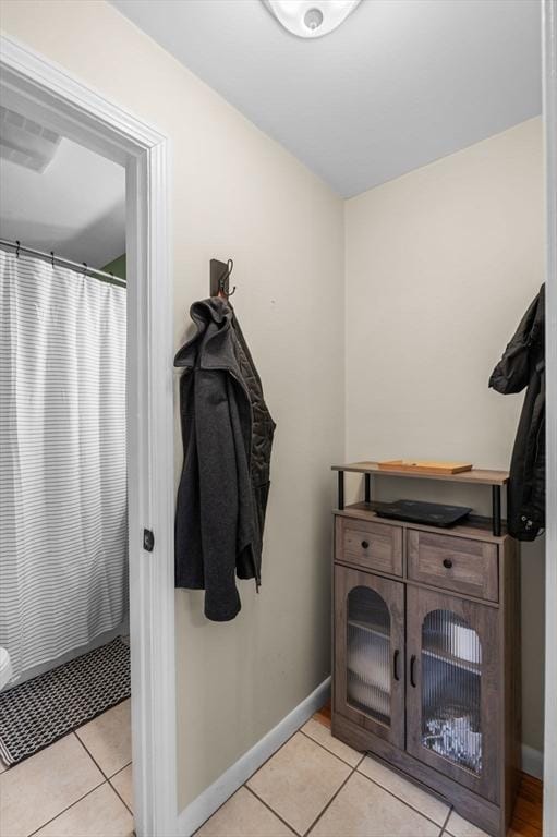 bathroom featuring a shower with shower curtain, baseboards, and tile patterned floors