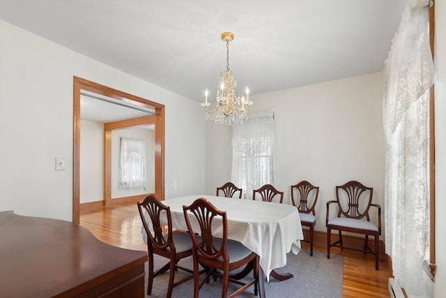 dining room with hardwood / wood-style floors, a baseboard radiator, and a chandelier