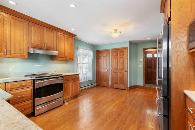 kitchen with light stone countertops, a baseboard radiator, appliances with stainless steel finishes, and light wood-type flooring