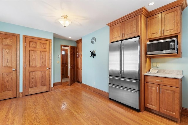 kitchen with light hardwood / wood-style flooring, light stone countertops, and appliances with stainless steel finishes