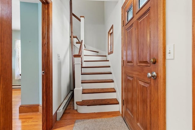 staircase featuring a baseboard heating unit and hardwood / wood-style floors