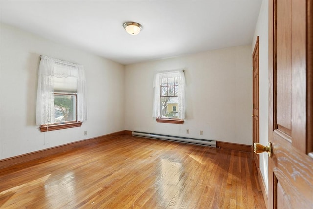 spare room featuring a baseboard heating unit and wood-type flooring