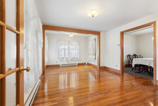 spare room featuring baseboard heating and light hardwood / wood-style floors