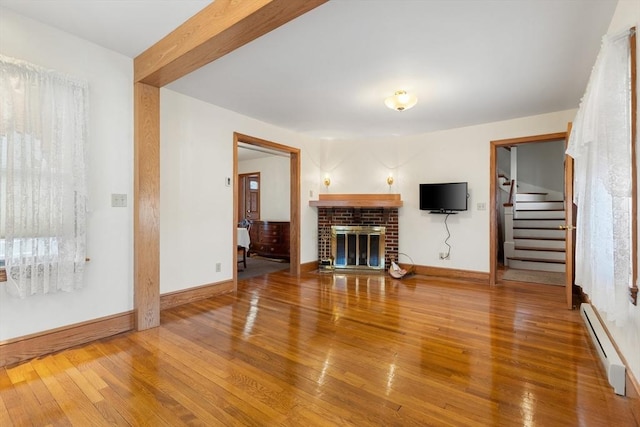 unfurnished living room with a brick fireplace, a baseboard radiator, and hardwood / wood-style floors