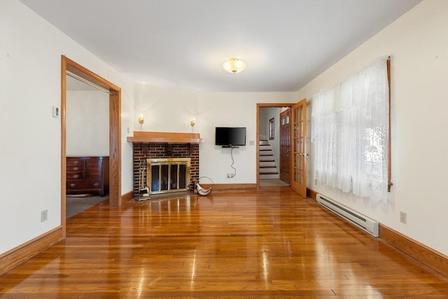 unfurnished living room with hardwood / wood-style flooring, a baseboard radiator, and a brick fireplace