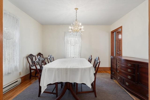 dining space with a baseboard heating unit, a notable chandelier, and hardwood / wood-style floors