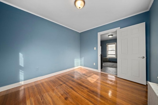 unfurnished room with wood-type flooring, crown molding, and baseboards