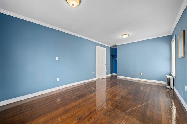 spare room with crown molding, radiator heating unit, wood finished floors, and baseboards