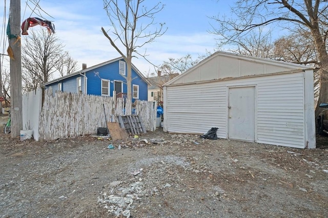 rear view of property with fence, board and batten siding, and an outbuilding