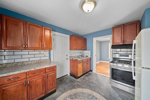 kitchen with stainless steel gas range oven, tasteful backsplash, freestanding refrigerator, concrete flooring, and under cabinet range hood