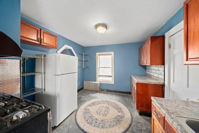 kitchen featuring light countertops, freestanding refrigerator, radiator, wall chimney exhaust hood, and gas range oven