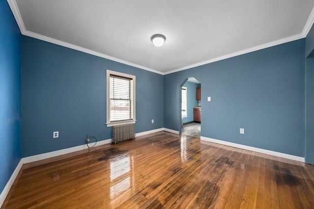 spare room featuring arched walkways, radiator heating unit, hardwood / wood-style flooring, and baseboards