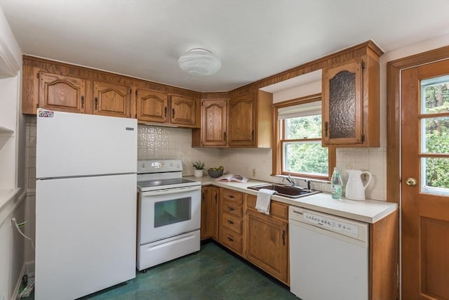 kitchen featuring white appliances, decorative backsplash, light countertops, brown cabinets, and a sink