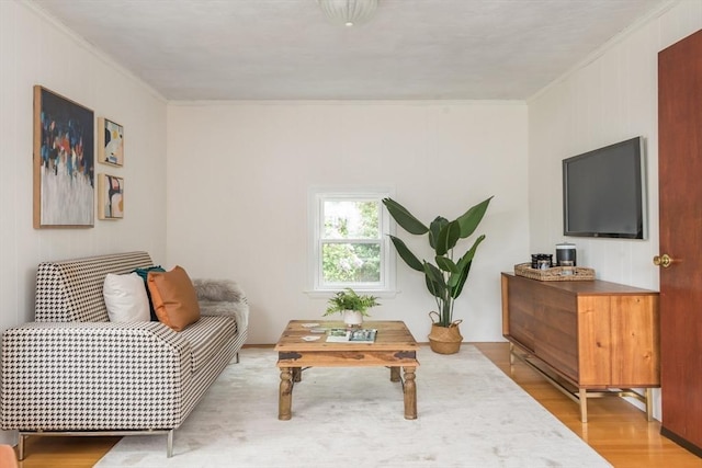 living area with crown molding and light wood-style floors