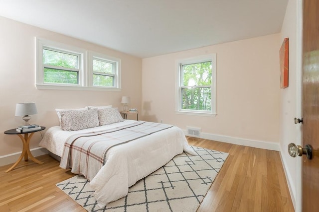 bedroom featuring multiple windows, baseboards, and light wood-style flooring