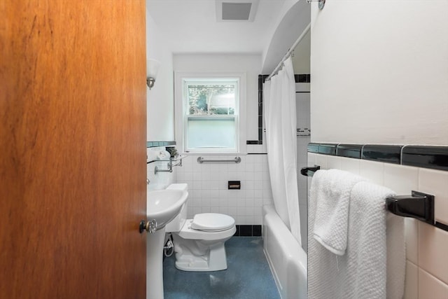 full bathroom with tile walls, toilet, a wainscoted wall, and shower / bath combo