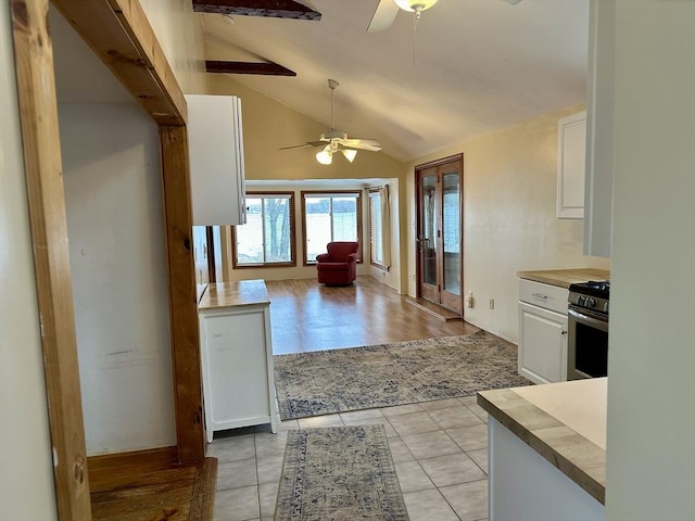 kitchen featuring vaulted ceiling with beams, white cabinetry, light tile patterned flooring, and stainless steel electric range