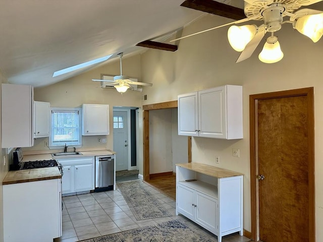 kitchen with a skylight, stainless steel dishwasher, sink, high vaulted ceiling, and white cabinetry