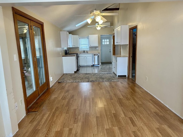 kitchen with light wood-type flooring, stainless steel dishwasher, vaulted ceiling, electric range, and white cabinets