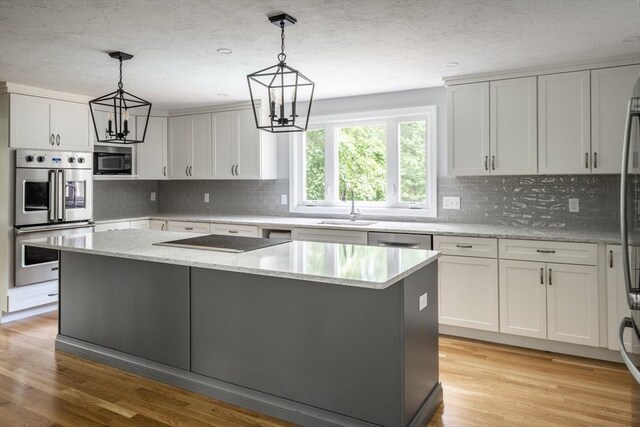 177 S St, Upton, MA 01568 - kitchen with appliances with stainless steel finishes, a sink, a kitchen island, decorative backsplash, and a textured ceiling