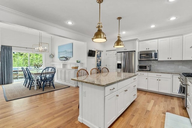 36 Village Way, Duxbury, MA 02332 - kitchen featuring appliances with stainless steel finishes, light wood-type flooring, crown molding, backsplash, and light stone counters