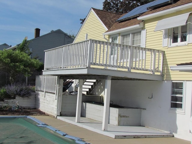 82 Laroche St, Ludlow, MA 01056 - back of property featuring roof mounted solar panels, a deck, a patio area, and a shingled roof
