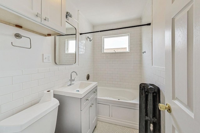 full bathroom with tiled shower / bath, tile walls, vanity, and toilet