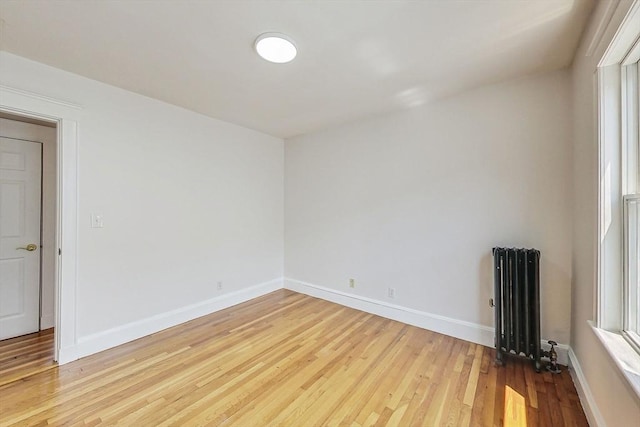 empty room featuring radiator heating unit and light hardwood / wood-style flooring