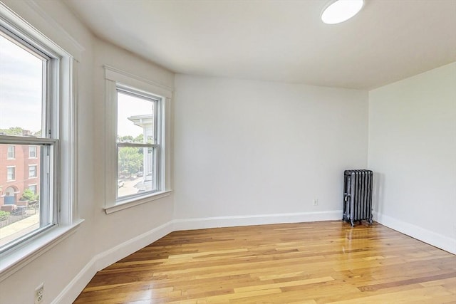 spare room featuring radiator heating unit and light wood-type flooring