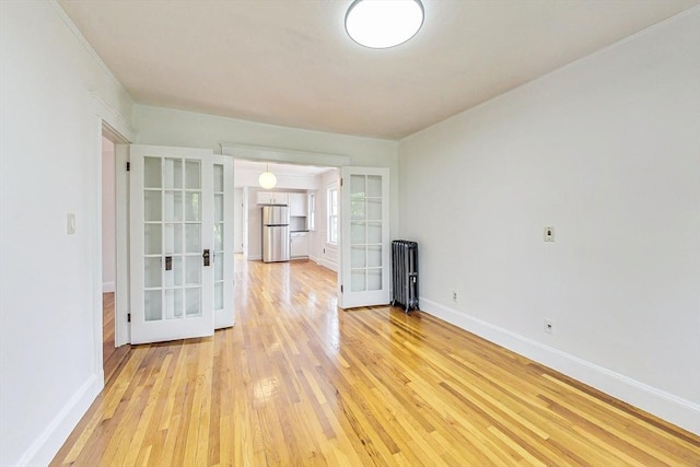 empty room featuring french doors and light wood-type flooring