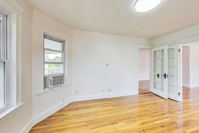 spare room with cooling unit, light hardwood / wood-style flooring, and french doors