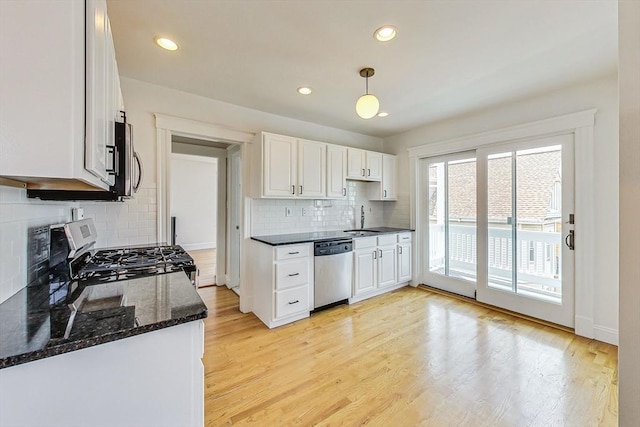 kitchen with sink, white cabinetry, light wood-type flooring, appliances with stainless steel finishes, and pendant lighting