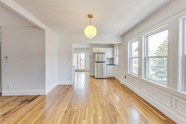 unfurnished living room with ornamental molding and light hardwood / wood-style flooring