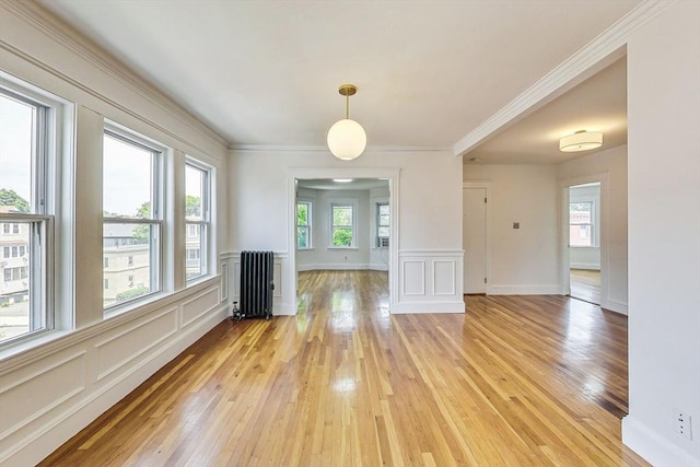 unfurnished dining area with ornamental molding, radiator heating unit, and light hardwood / wood-style floors