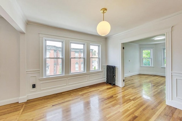 empty room with hardwood / wood-style floors, ornamental molding, and radiator heating unit