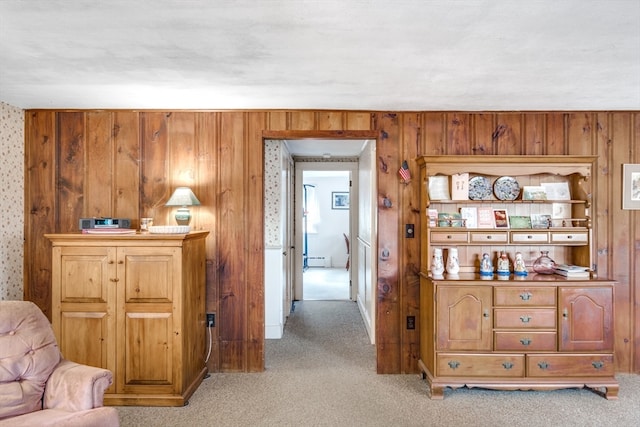 hallway with wood walls, light carpet, and a baseboard heating unit