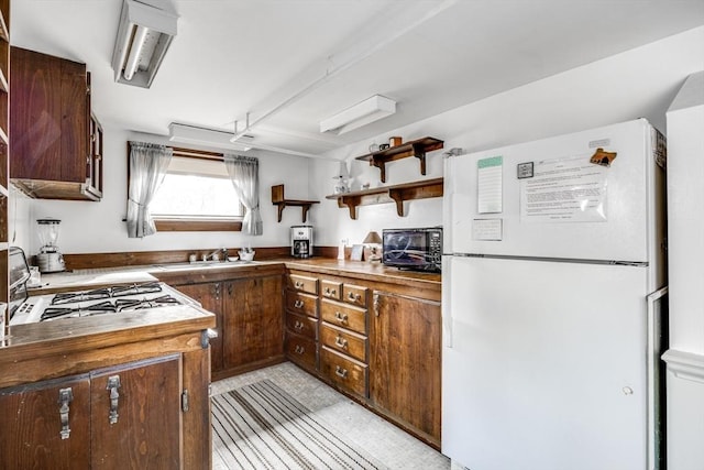 25 First Ave, Wellfleet, MA 02667 - kitchen featuring freestanding refrigerator, a sink, open shelves, and dark brown cabinetry
