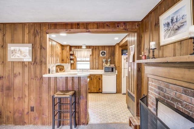 25 First Ave, Wellfleet, MA 02667 - kitchen with white appliances, wood walls, brown cabinets, a brick fireplace, and open shelves