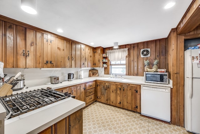 kitchen with wood walls, sink, and white appliances