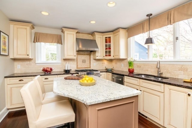 kitchen with cream cabinets, a sink, and wall chimney exhaust hood